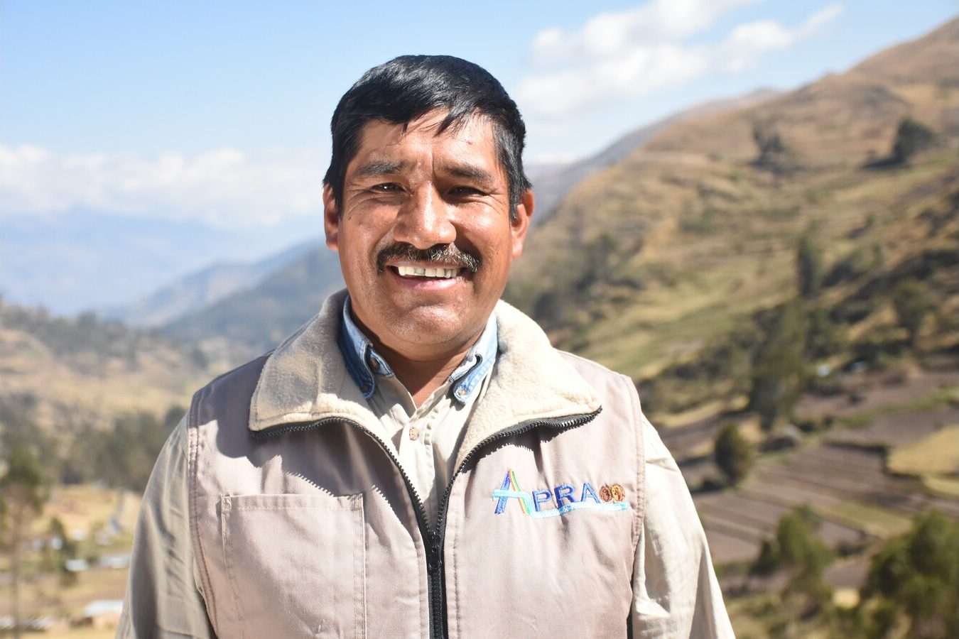 Productor de papa sonriendo, con chaleco de su asociación, en el valle de Morochata
