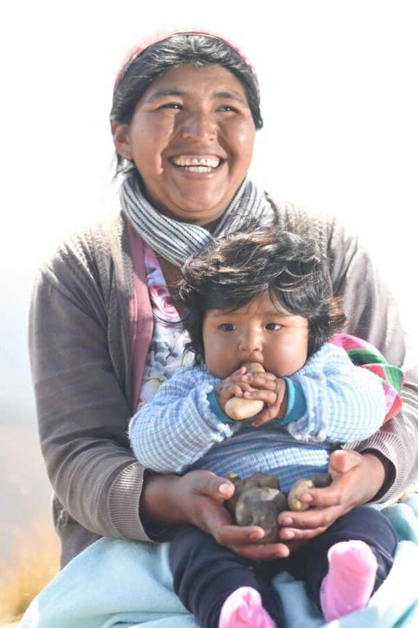Madre con su bebé mostrando papas nativas