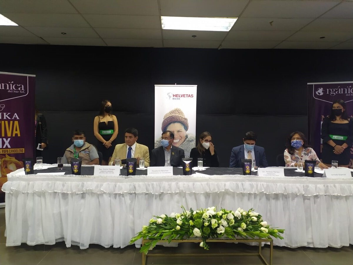 Mesa principal del lanzamiento de Minka Nativa Mix, con banners de Orgánica y Helvetas