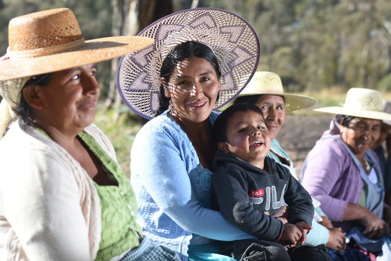 Mujeres productoras con sus sombreros, junto a una niña, en el campo
